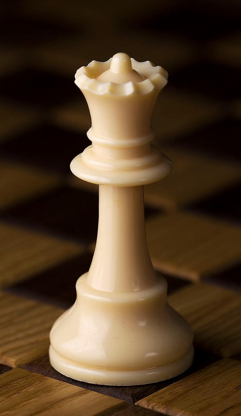A white chess queen, lit warmly from one side